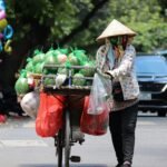 a woman pushing a cart filled with lots of produce